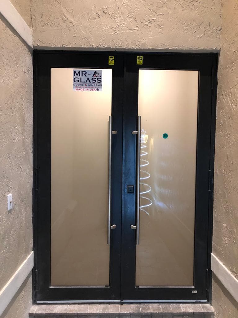 Front entry door replacement with impact rated glass sidelites and transom window on a Florida home with decorative hardware