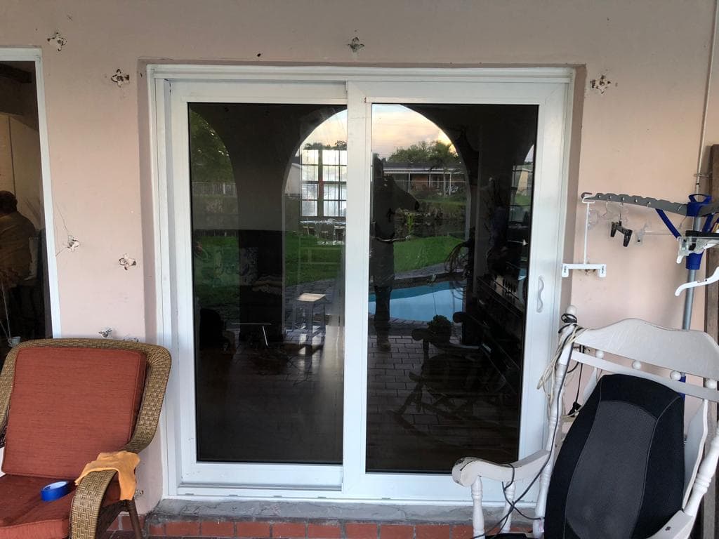 Large impact windows installed in a living room of a Florida home providing natural light and hurricane protection with view of tropical landscape